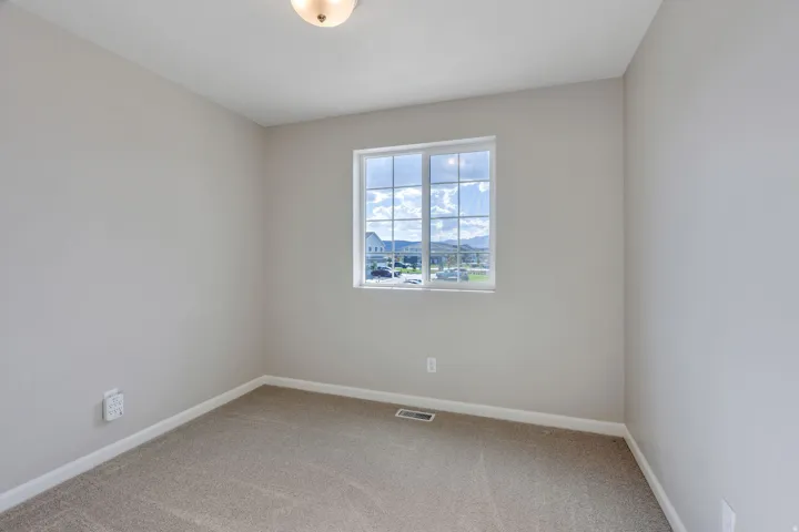 Neutral-toned walls with carpet flooring, featuring a grid-pattern window and a flush-mount ceiling light