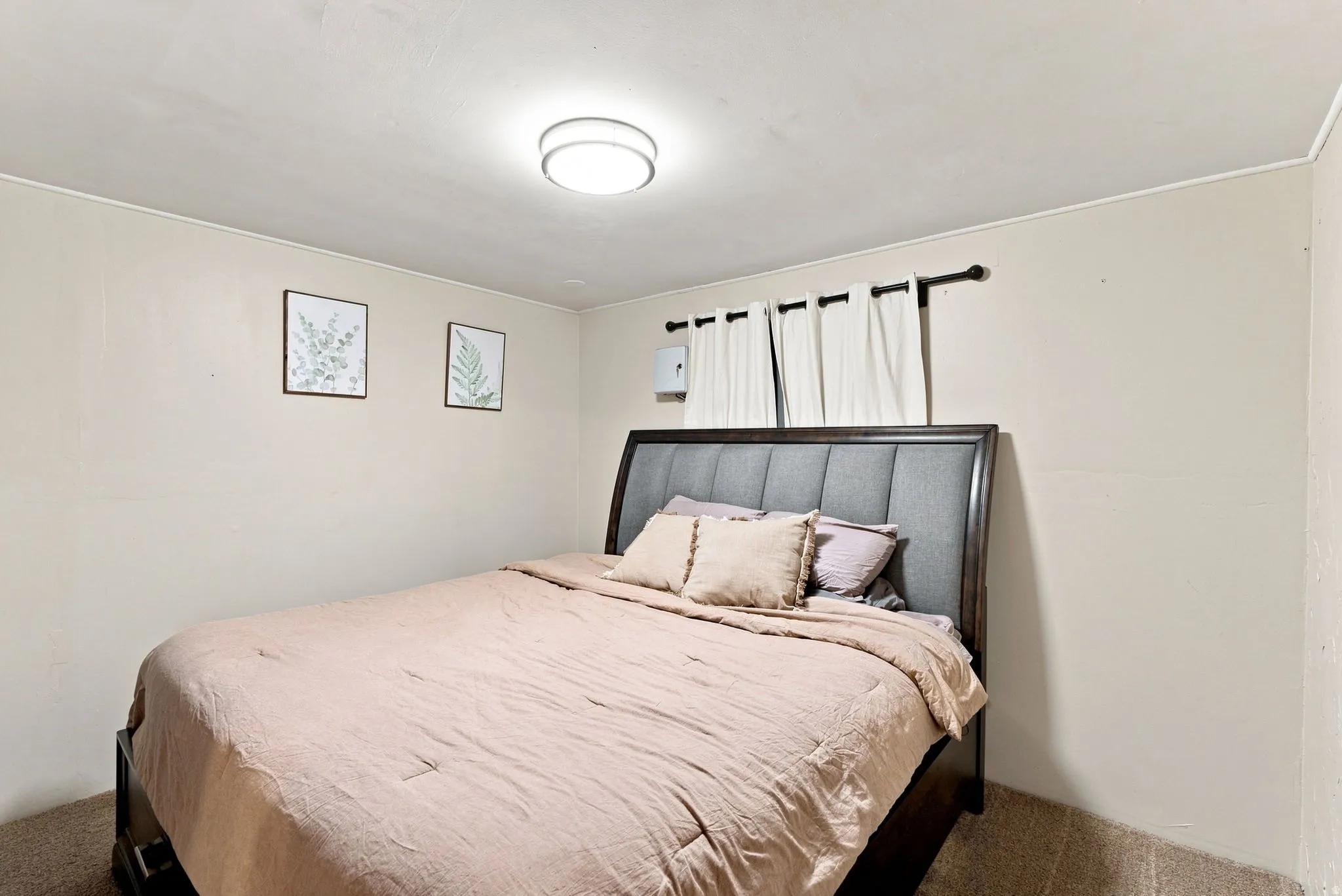 Flush-mount ceiling light fixture, neutral wall color, and window with curtain rod