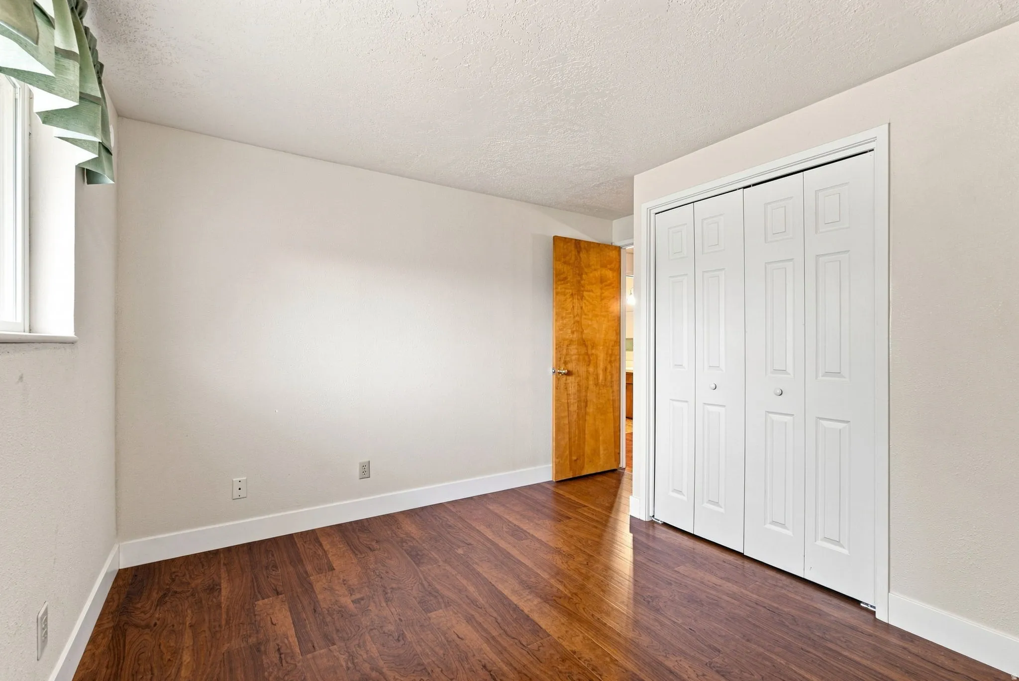 Wood-finish flooring, white bi-fold closet doors, and light-toned walls