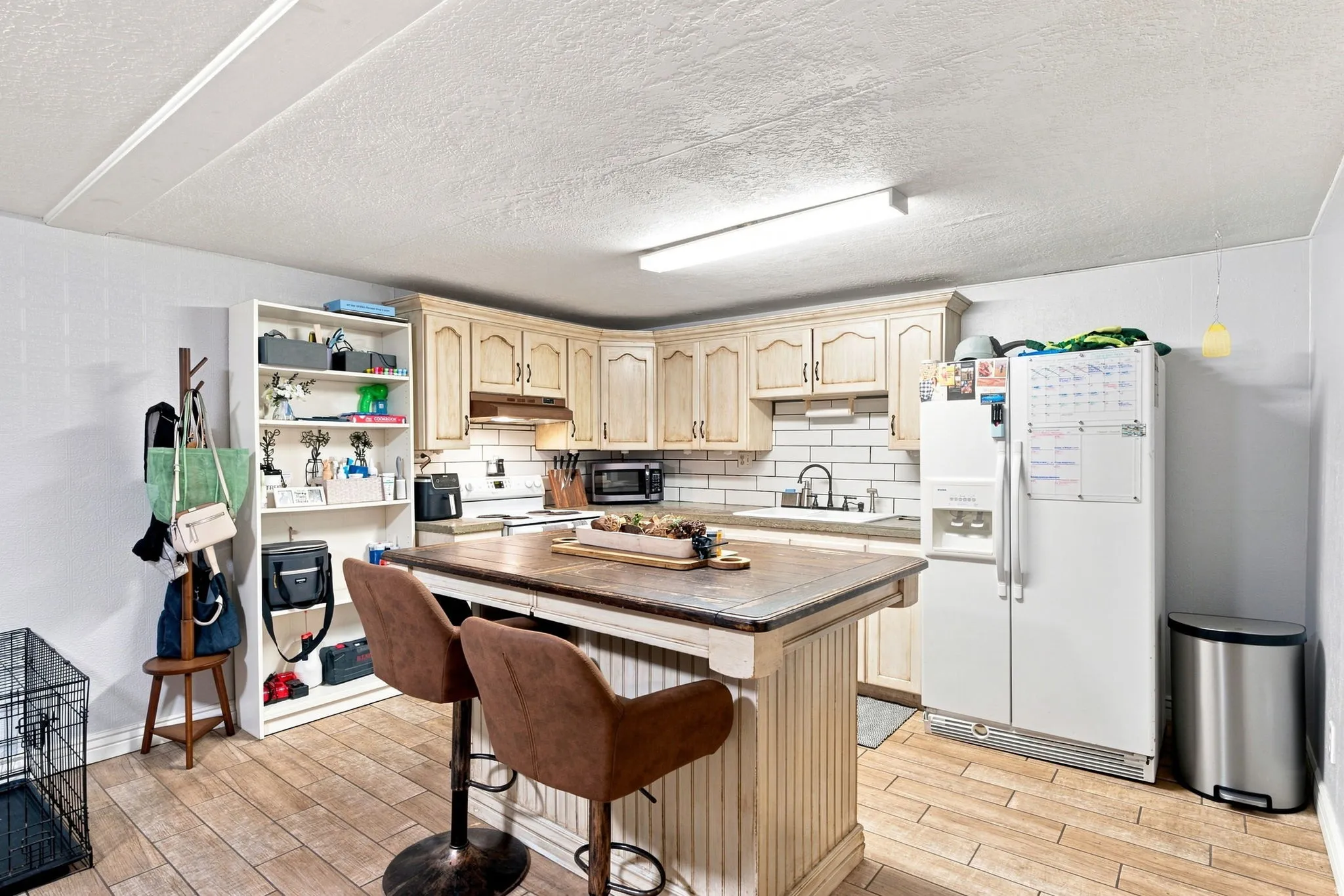 Kitchen featuring an island with seating, white subway tile backsplash, cream-finish cabinetry, and wood-finish flooring