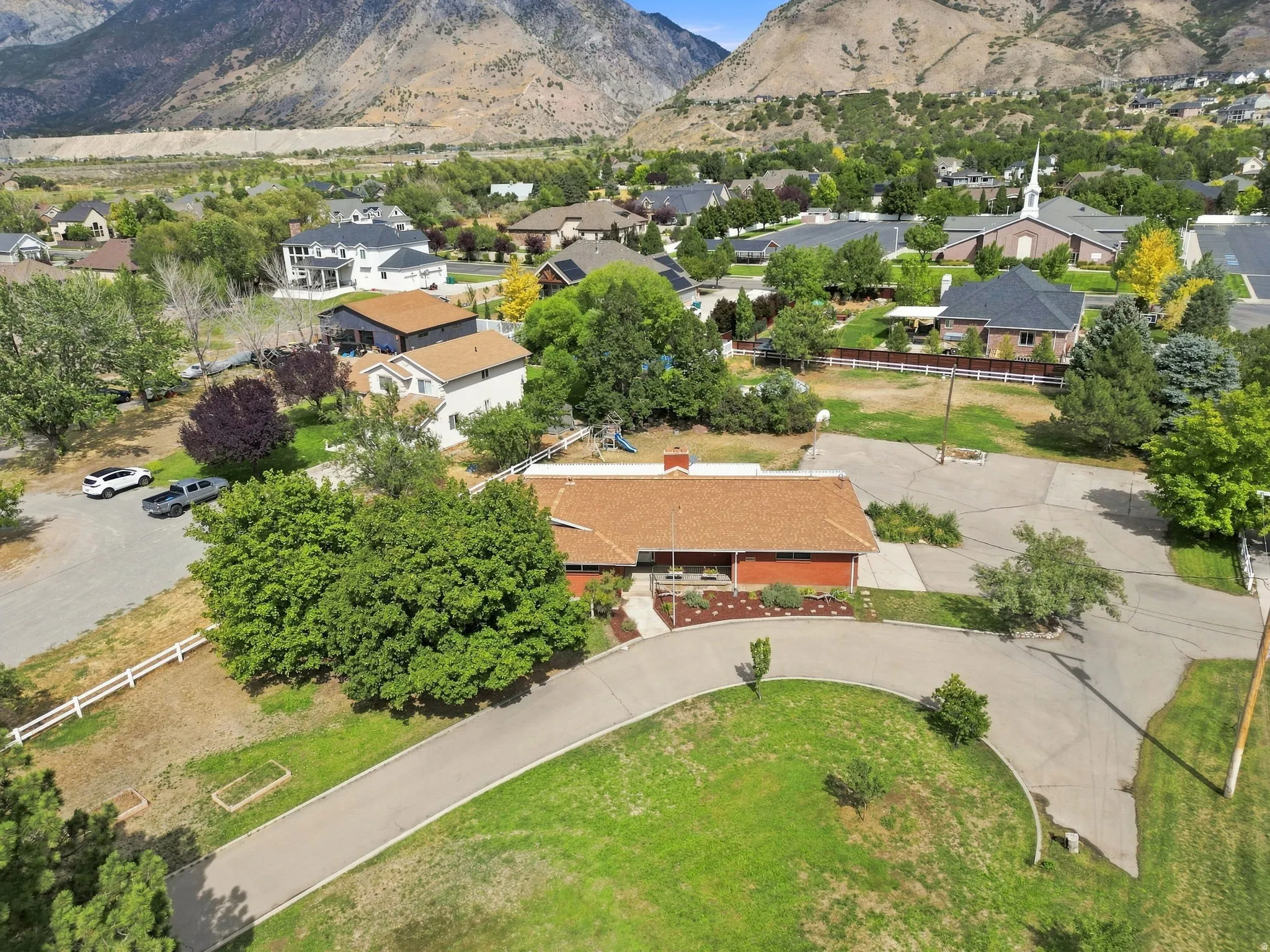 Expansive lot with mature trees, red brick exterior, and a circular driveway