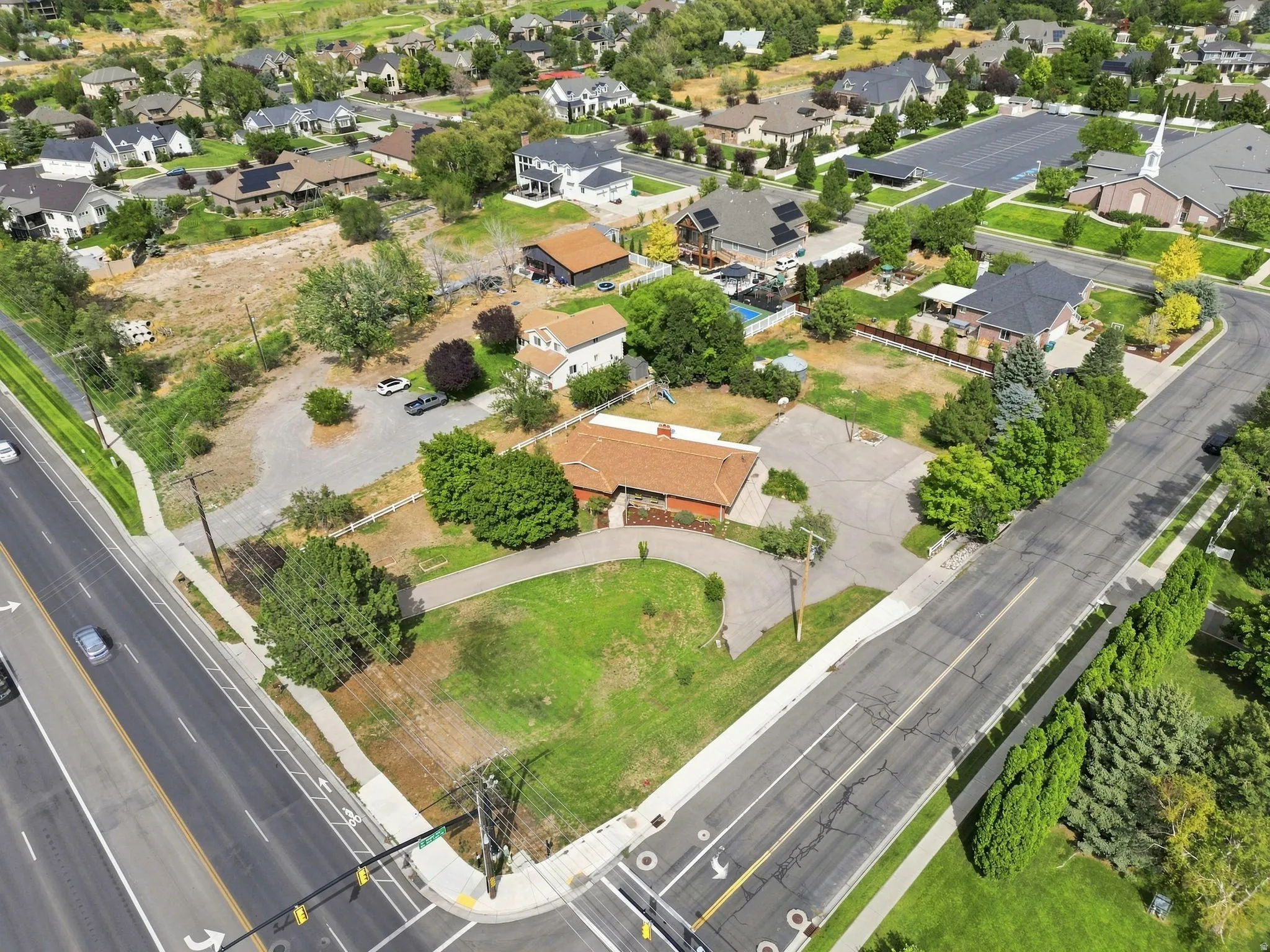 Expansive corner lot featuring mature trees, paved driveways, and surrounding green spaces