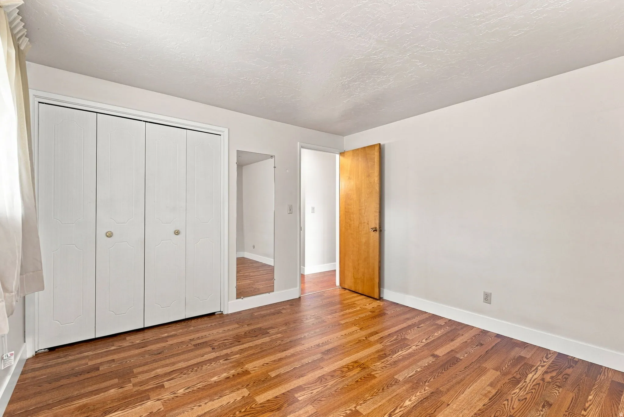 Wood-finish flooring, light-toned walls, and a full-length mirror
