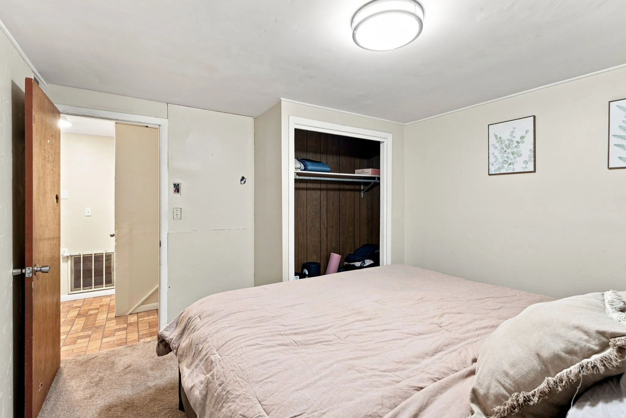 Spacious bedroom featuring hardwood flooring, generous natural light from multiple windows, and ample closet storage with dark wood-finish doors