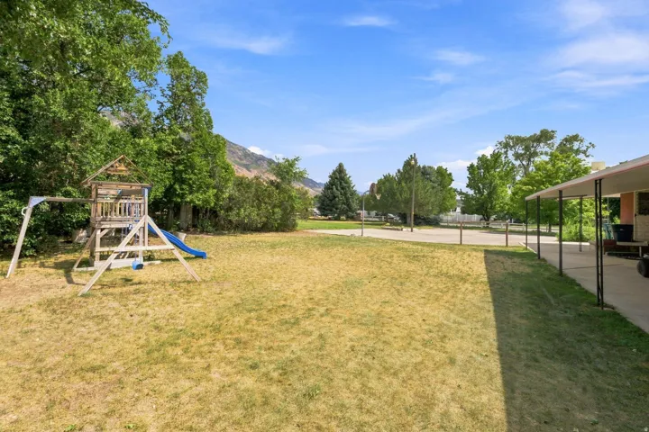 Spacious outdoor area with mature trees and a covered patio