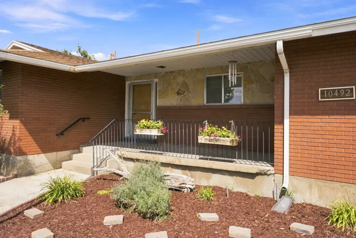 Brick exterior with stone accents, a covered porch, and mature landscaping