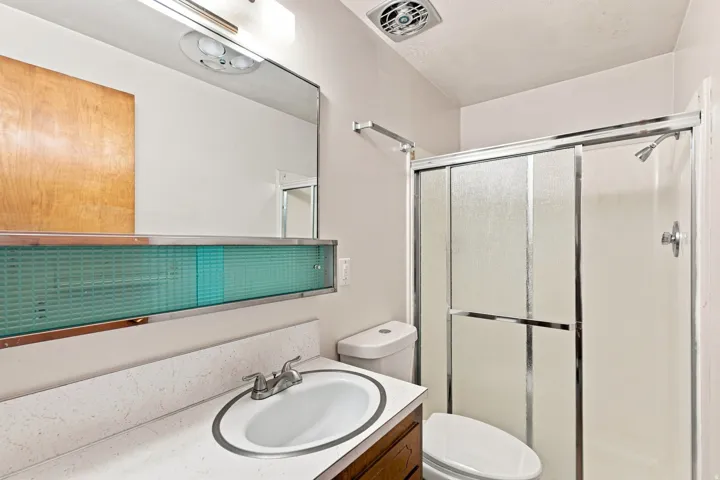Single vanity with integrated sink, chrome faucet, and overhead lighting