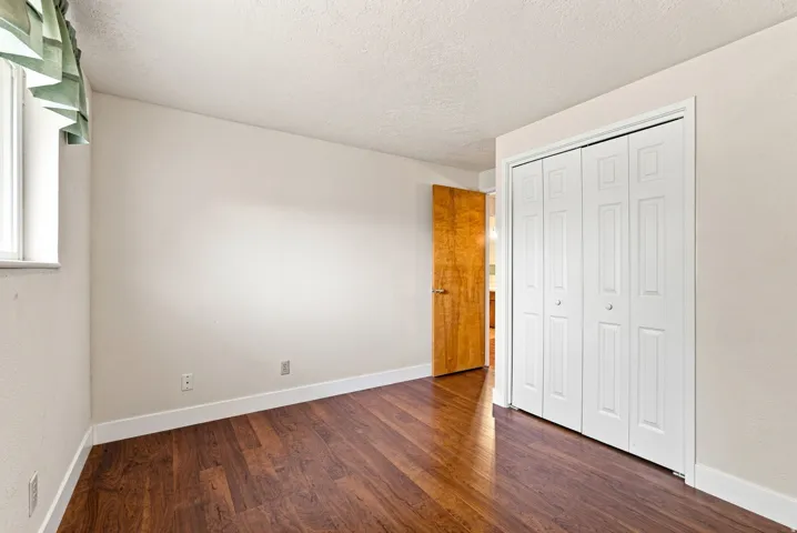 Wood-finish flooring, white bi-fold closet doors, and light-toned walls