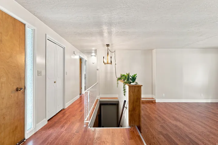 Wood-finish flooring throughout, white painted walls, and a modern ceiling-mounted light fixture