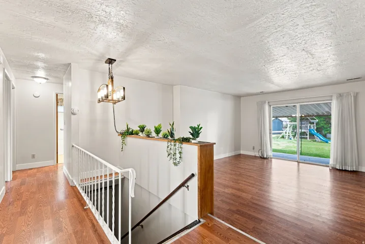 Hardwood-finish flooring throughout, white painted walls, and a contemporary chandelier
