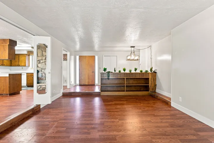 Wood-finish flooring throughout, stone-clad architectural detail, built-in shelving, and a modern chandelier