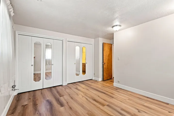 Wood-finish flooring throughout, bright white walls, and bi-fold closet doors with mirrored panels