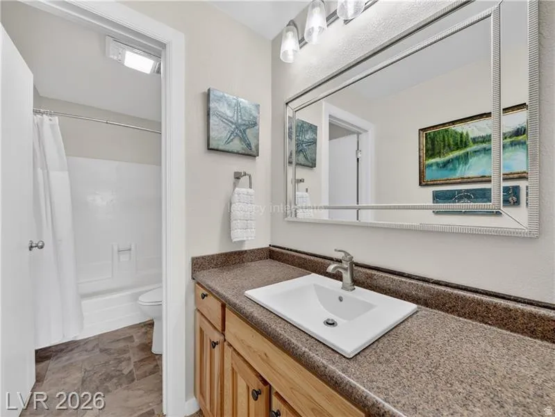 Vanity with a built-in rectangular sink and brushed nickel faucet, large framed mirror, wood-finish cabinetry, and a countertop with integrated backsplash