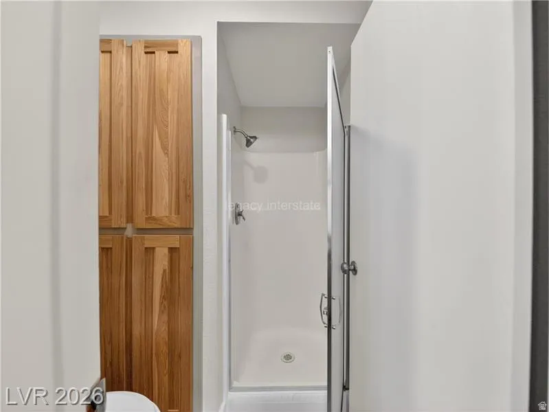 Walk-in shower with a glass enclosure and built-in wood cabinetry