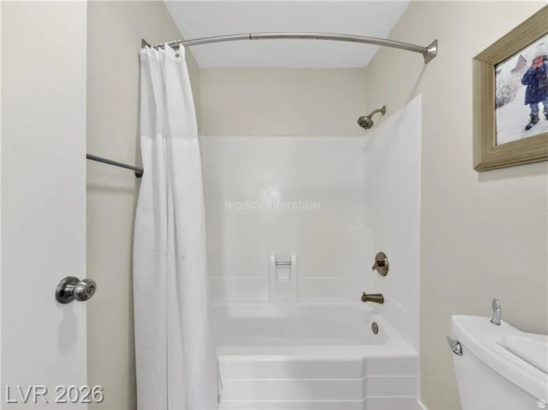 Bathtub with integrated shower, wall-mounted shower head, and bronze-finish fixtures