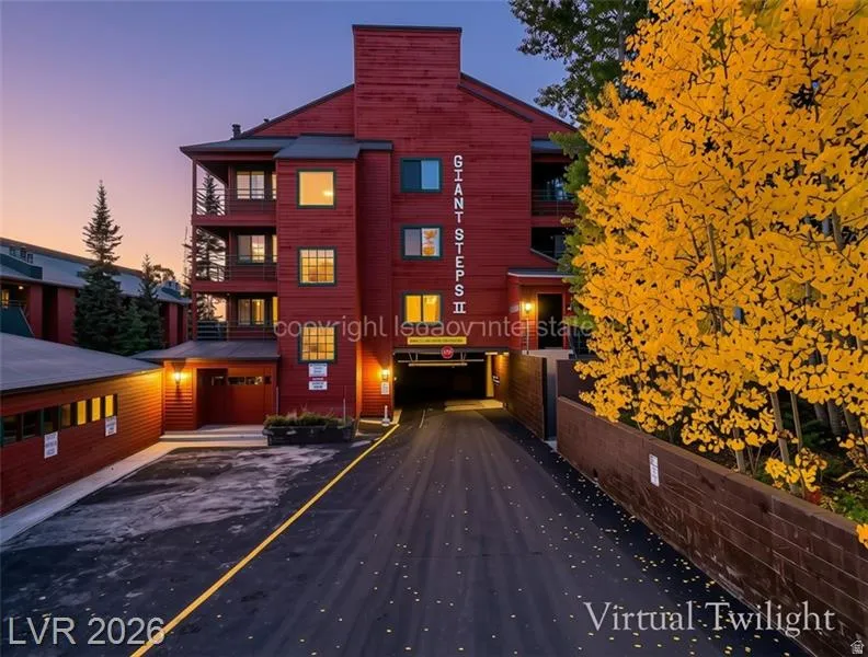 Multi-story building with a red wood-panel exterior, featuring multiple balconies, an integrated covered parking area, and a lower-level garage