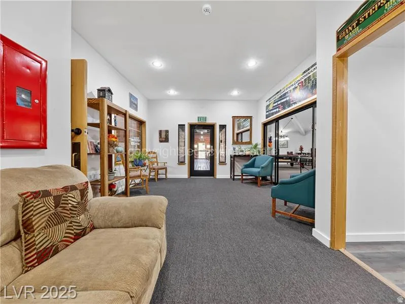 Recessed ceiling lighting illuminates the carpeted hallway, featuring wood-finish shelving and a wood-framed mirror