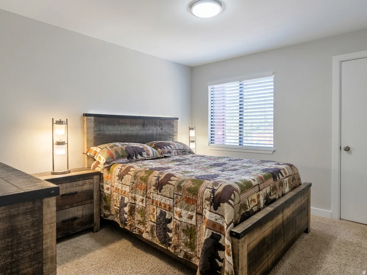 Carpeted flooring, white walls, window with blinds, flush-mount ceiling light, and a white door with a round knob