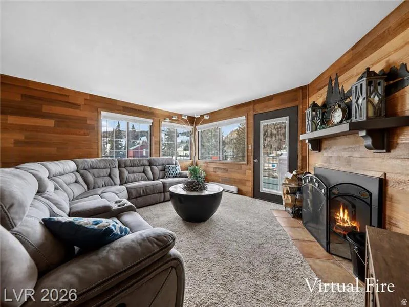 Wood-paneled walls with multiple windows, a built-in fireplace with a hearth, and a dark wood mantel