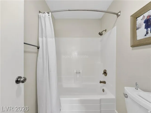 Bathtub with integrated shower, wall-mounted shower head, and bronze-finish fixtures