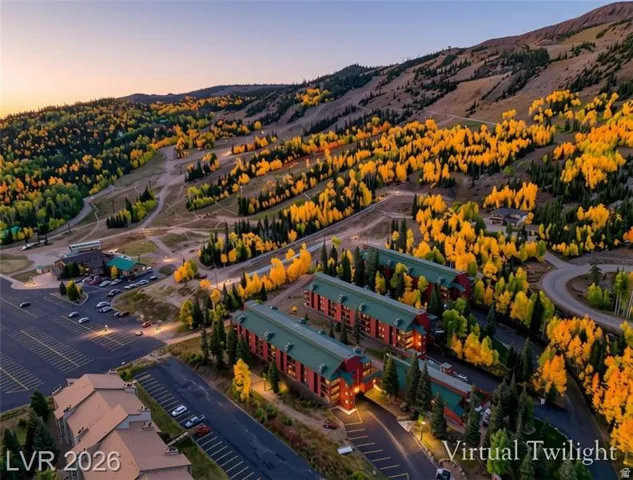 Mountainous terrain with varied tree coverage, large parking areas, and multiple multi-story buildings