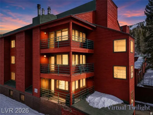 Multi-story exterior featuring red wood siding, multiple private balconies with metal railings, and a dark-colored roofline