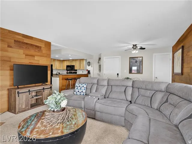 Open-concept living area featuring a wood-panel accent wall and wood-finish cabinetry