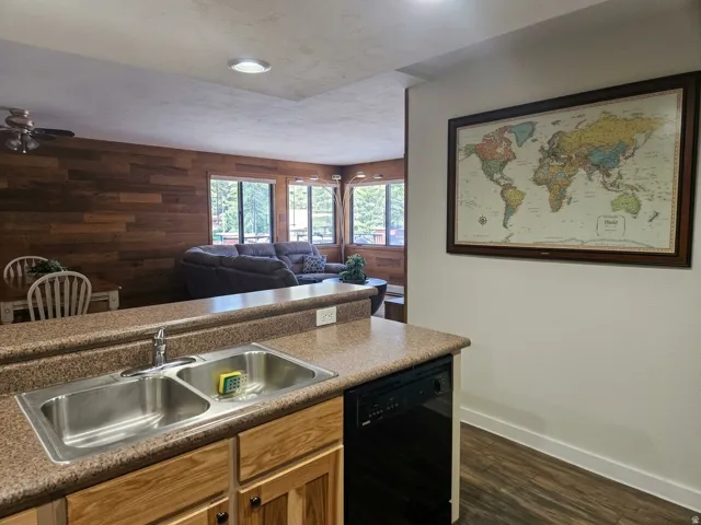 Kitchen featuring a stainless steel double basin sink, laminate countertops, wood-finish cabinetry, and a built-in dishwasher