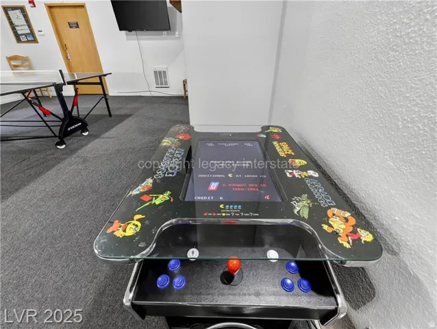 Recreational area with an arcade game and a ping pong table, featuring textured wall finishes and wood-finish doors