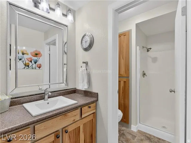 Vanity with a rectangular undermount sink, a countertop with integrated backsplash, and wood-finish cabinetry