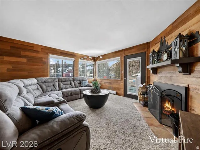 Wood-paneled walls with multiple windows, a built-in fireplace with a hearth, and a dark wood mantel