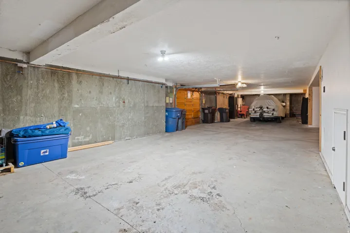 Concrete flooring, exposed ceiling beams, and overhead lighting fixtures