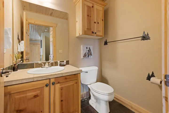 Wood-finish vanity with an oval sink, single-handle faucet, and tile backsplash