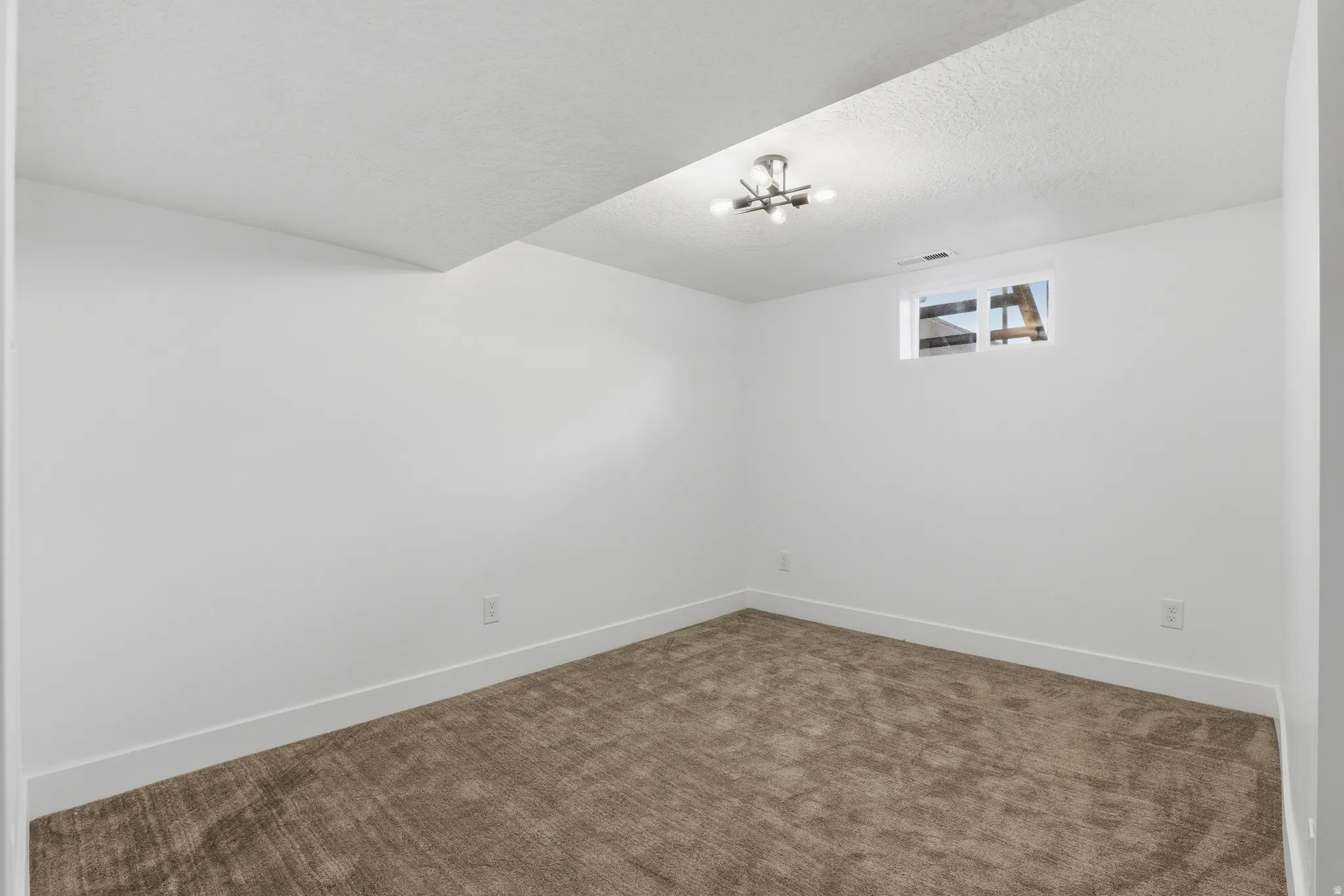 Recessed lighting and a single window complement a carpeted floor