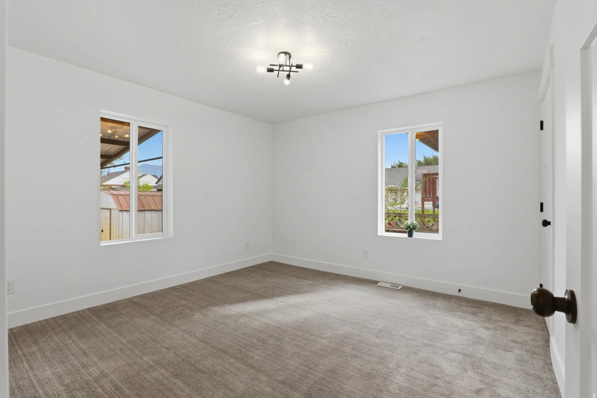 Neutral wall finishes, dual windows, textured carpet flooring, and a modern ceiling light fixture