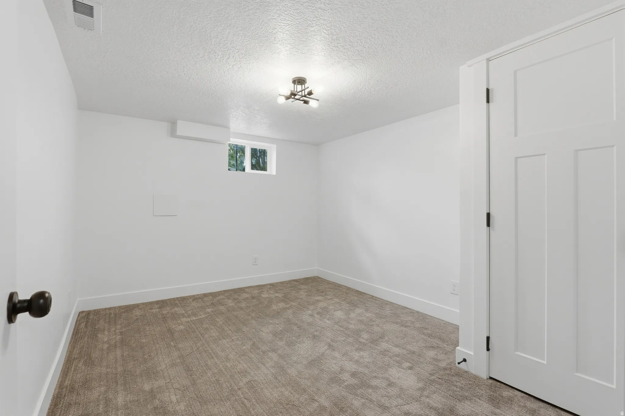 Recessed window with white trim, wall-mounted light fixture, carpeted flooring, and white paneled door with black hardware