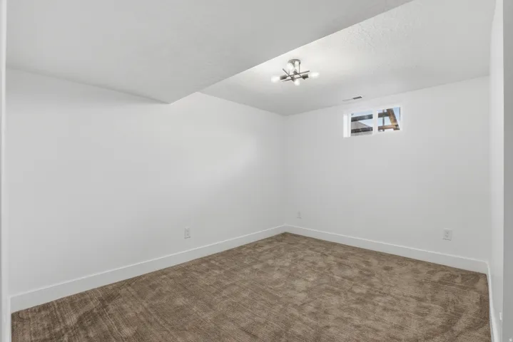 Recessed lighting and a single window complement a carpeted floor