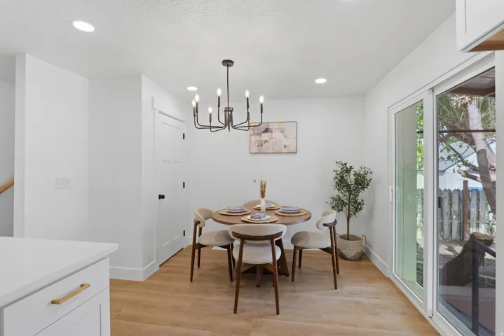 Recessed lighting, wood-finish flooring, sliding glass door, white cabinetry, and a contemporary chandelier