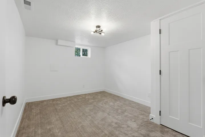 Recessed window with white trim, wall-mounted light fixture, carpeted flooring, and white paneled door with black hardware