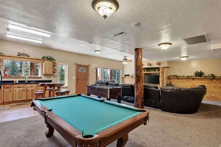 Recreation room featuring a pool table, wood-finish cabinetry, and a log-accented support column