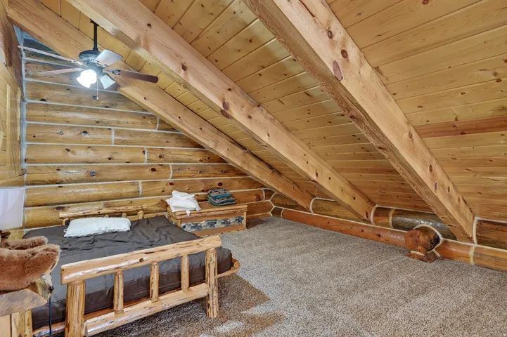 Vaulted ceilings with exposed wood beams, wood paneling, log walls, and carpeting