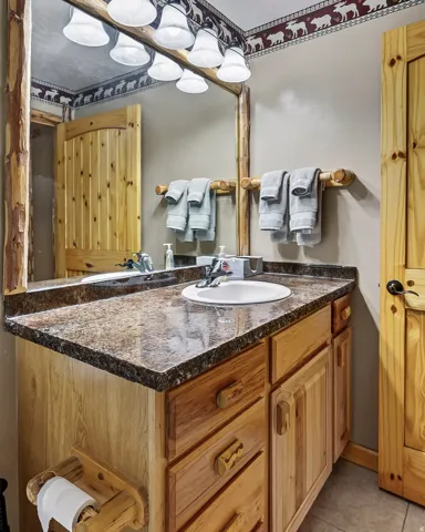 Built-in vanity with a single basin sink, wood-finish cabinetry, and a stone-look countertop