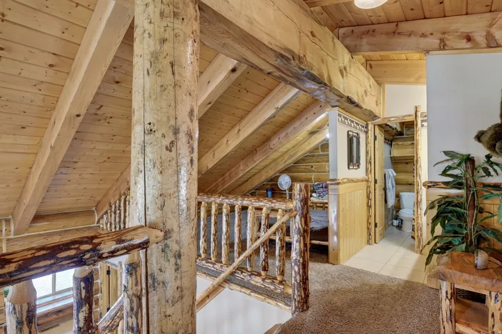 Exposed wood beam construction, natural wood plank ceilings, log-style railing, and wood-finish door frames