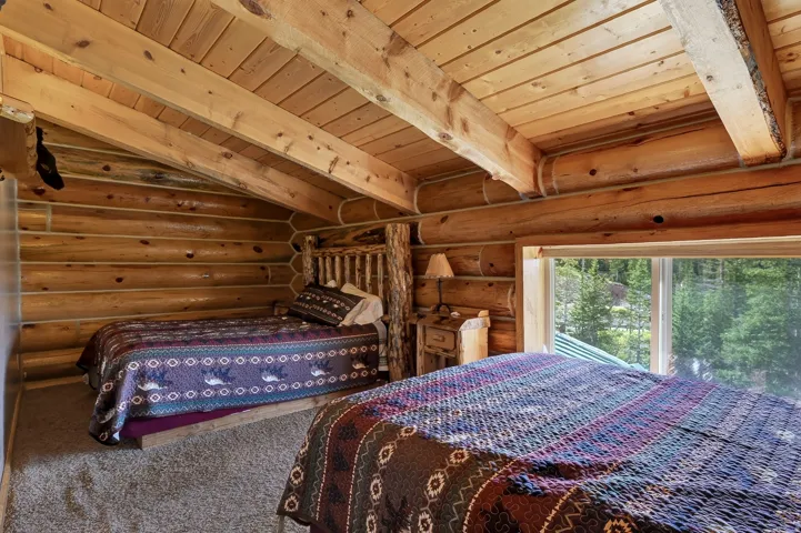 Log wall construction with exposed wood beam ceiling, sloped wood ceiling, and a large window