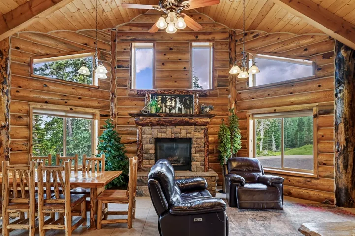 Log wood interior with a stone fireplace, wood-finish flooring, and multiple windows