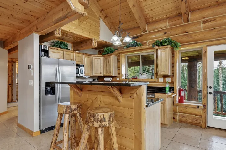 Kitchen featuring natural wood cabinetry, stainless steel appliances, a breakfast bar, and tile flooring