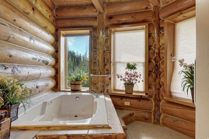 Log cabin interior featuring a built-in jetted tub, multiple windows with natural light, and tile flooring