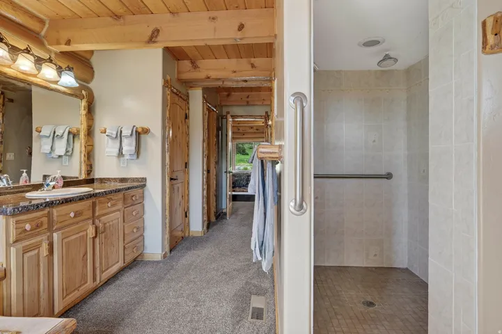 Wood vanity with a stone countertop, framed mirror, and decorative light fixture