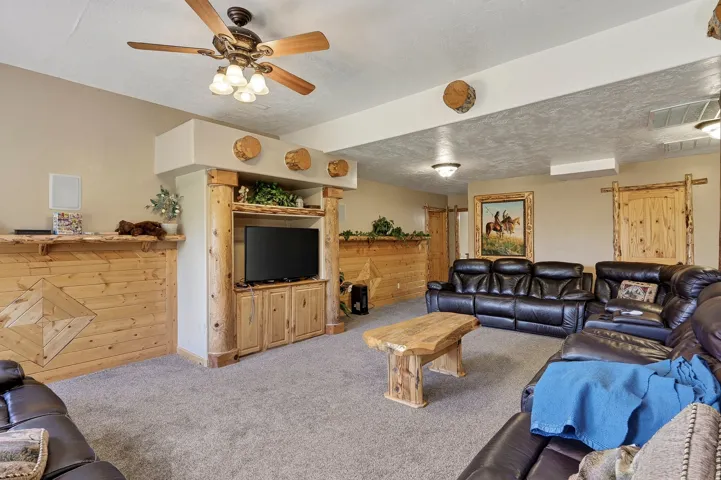 Wood-paneled wall with decorative inlay, built-in media center with wood-finish cabinetry, and rustic wood ceiling beams