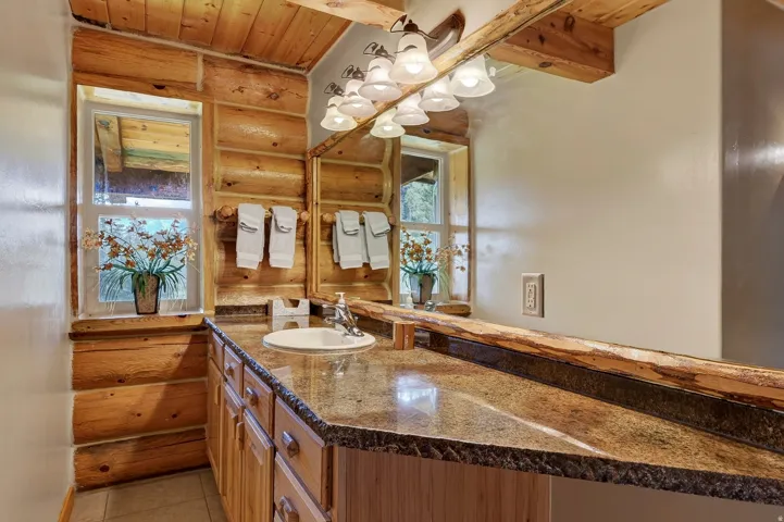 Bathroom featuring a single vanity with an integrated sink, stone-finish countertop, wood cabinetry, and a multi-bulb light fixture